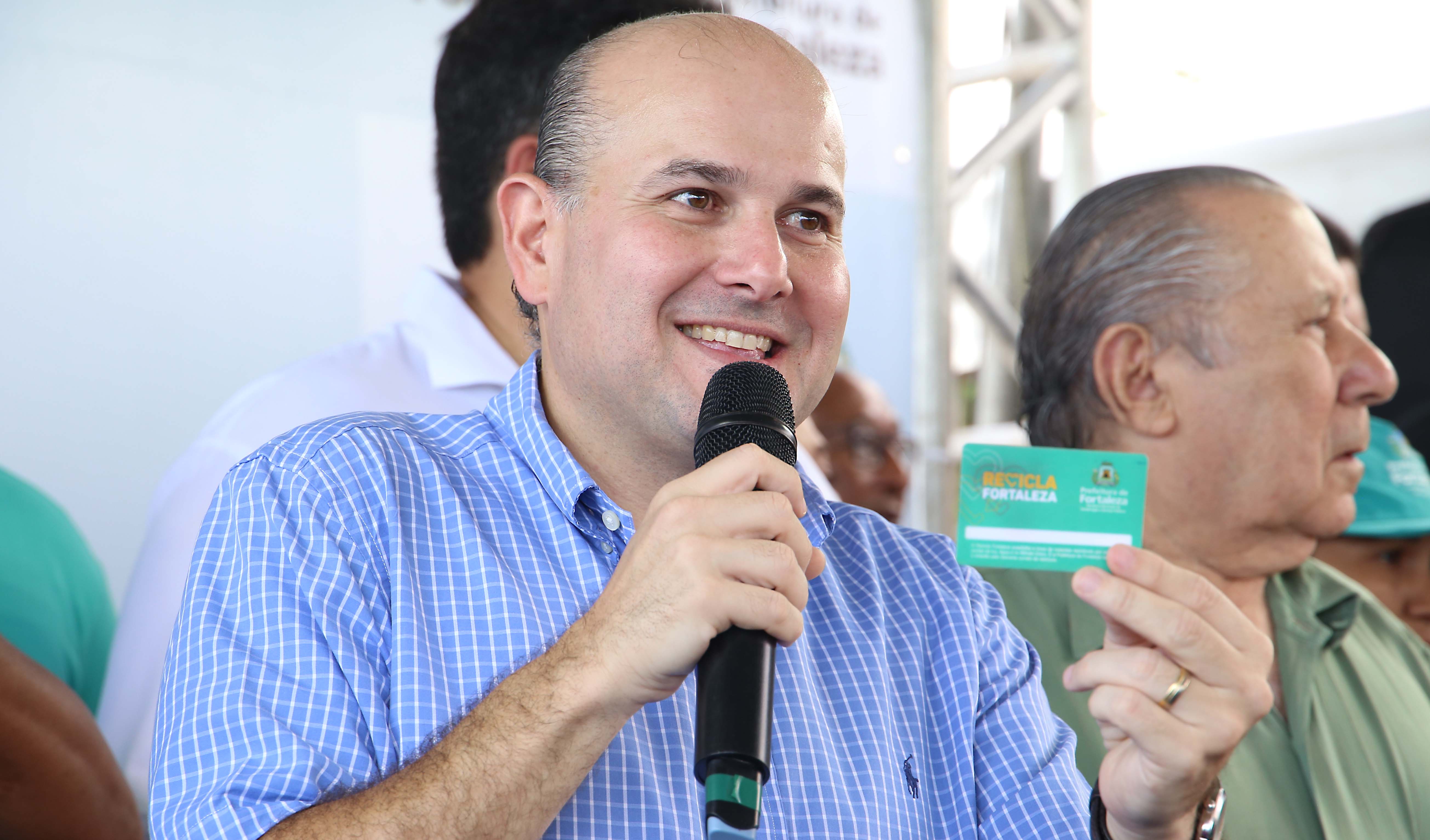 prefeito segura o cartão do programa Recicla Fortaleza enquanto fala ao microfone